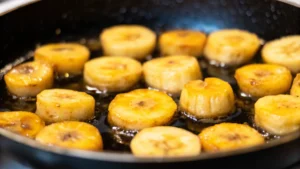  Close-up of caramelized bananas with vanilla ice cream and caramel sauce on a rustic plate.
