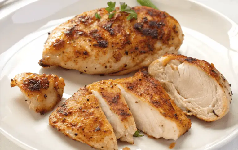Perfectly broiled chicken breasts on a plate, garnished with fresh herbs and lemon slices."