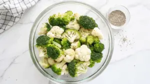 Roasted broccoli and cauliflower with garlic and parmesan served on a rustic wooden tray.