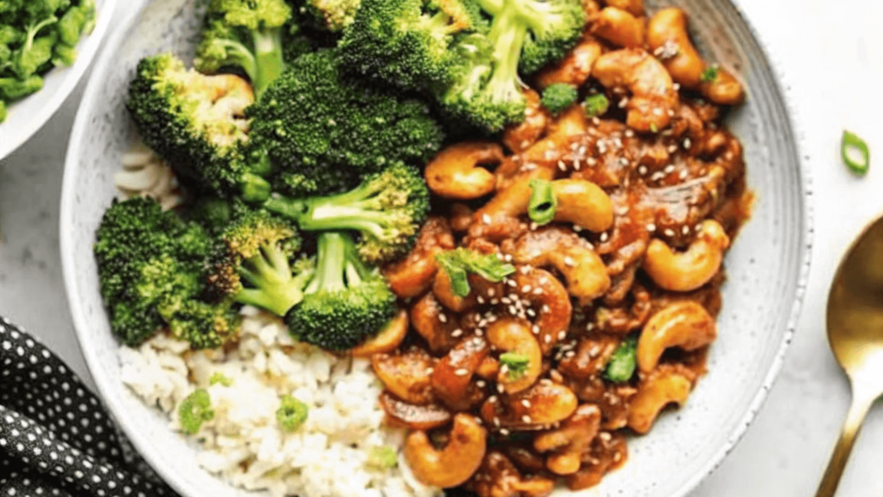 Cashew Chicken Bowl with Broccoli and Rice Healthy bowl of cashew chicken with broccoli and steamed rice, garnished with sesame seeds.