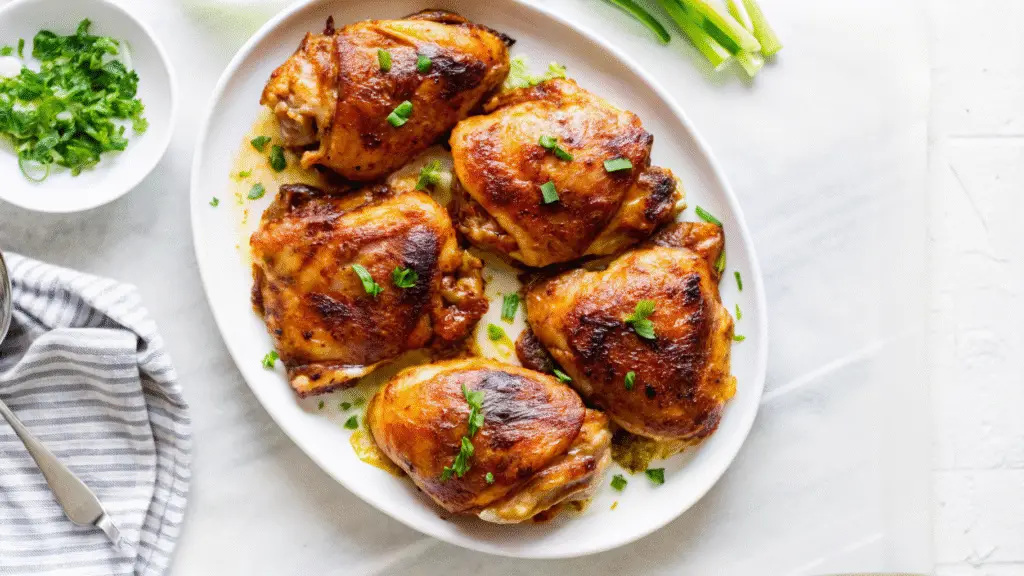 Honey Lemon Ginger Glazed Chicken in cast iron skillet with lemon slices and fresh herbs, golden-brown and glazed to perfection