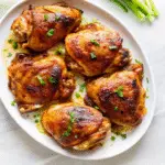 Honey Lemon Ginger Glazed Chicken in cast iron skillet with lemon slices and fresh herbs, golden-brown and glazed to perfection